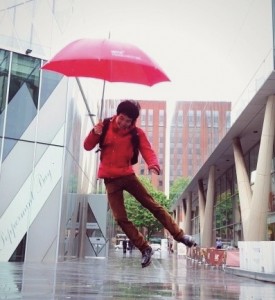 Male student holding umbrella in the rain