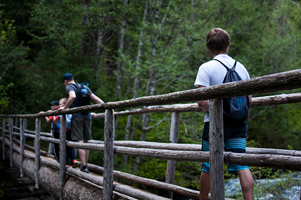 INTO OSU students hiking on a wooden bridge through the forest.